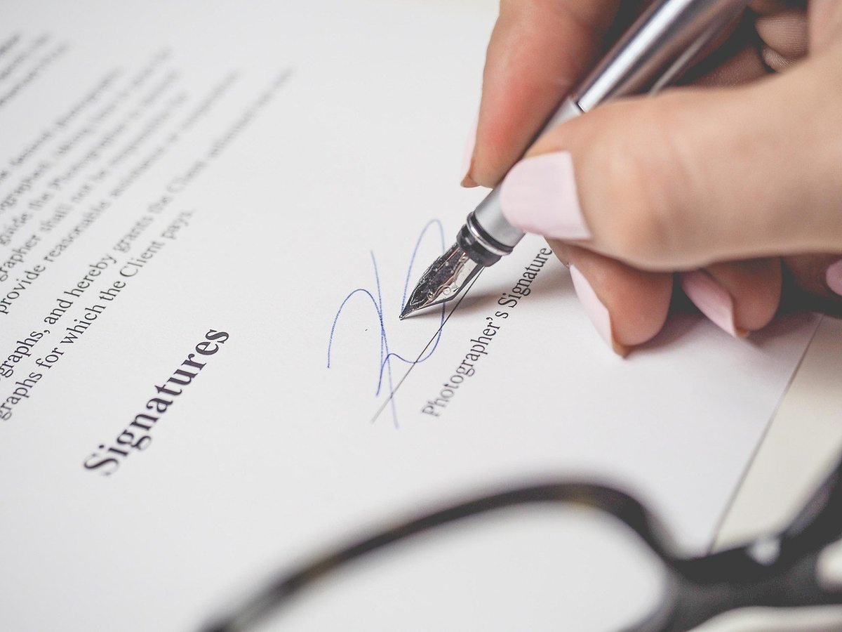 Signature manuscrite sur un document avec lunettes de lecture