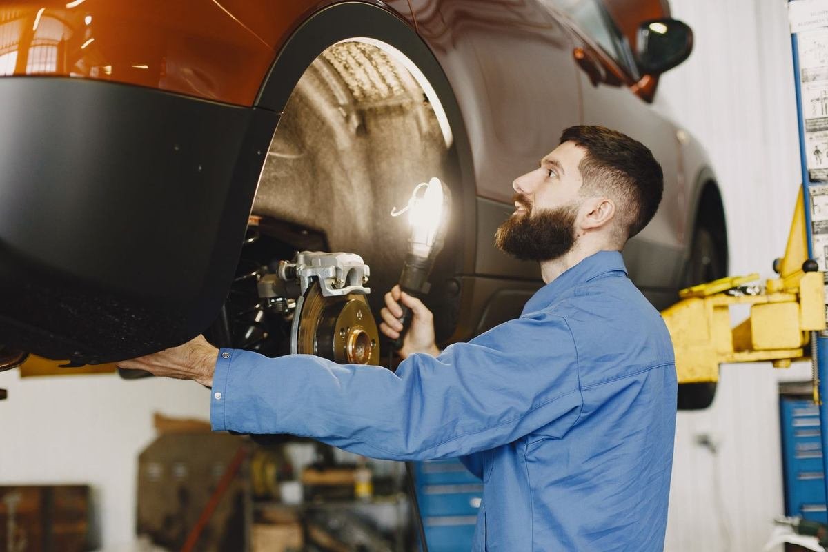 Mécanicien examine la roue arrière d'une voiture sur une nacelle