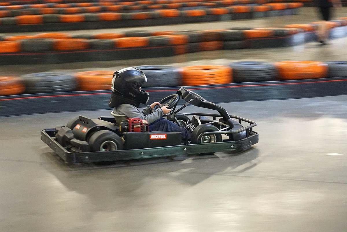 Un conducteur avec casque pilote un karting intérieur Un conducteur avec casque pilote un karting intérieur