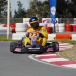 Un pilote en combinaison jaune pilote un kart sur virage