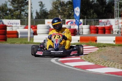 Un pilote en combinaison jaune pilote un kart sur virage