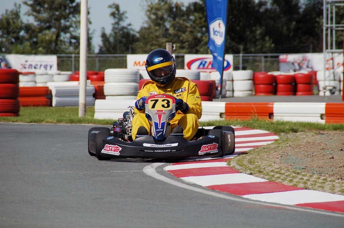 Un pilote en combinaison jaune pilote un kart sur virage