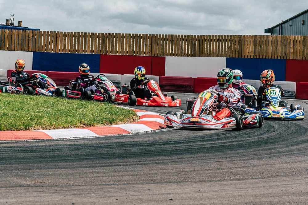 Plusieurs pilotes dans des karting dérapent dans un virage de circuit