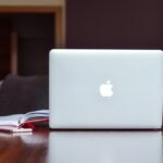 Ordinateur portable Apple sur table en bois avec cahier ouvert