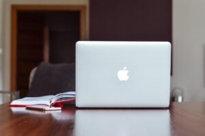 Ordinateur portable Apple sur table en bois avec cahier ouvert