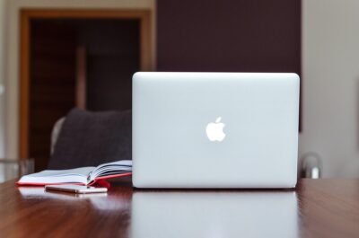 Ordinateur portable Apple sur table en bois avec cahier ouvert